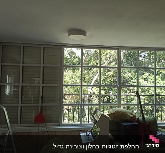 חלון זכוכית גדול עם נוף עצים ירוקים